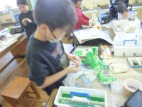 ３年生図画工作科「空きようきのへんしん」の授業の様子です。前回、容器に紙粘土をつけて、空き容器を生き物や建物、小物入れなどに変身しました。その容器に色つけをしました。カラフルに色をつける子、生き物の色にする子など、イメージを膨らませながら、オリジナルの作品を一生懸命に作っていました。